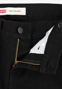 Fekete Levi's 510 Skinny farmernadrág arany cipzárral, fekete gombbal és nyomtatott díszítésű, fehér bélésével rendelkezik. Pamut anyag, slim fit dizájn.