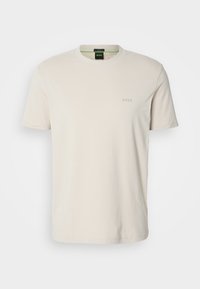 T-shirt uni beige clair à manches courtes avec col rond, petit logo BOSS embossé sur la poitrine gauche et étiquette noire à l'intérieur du col.