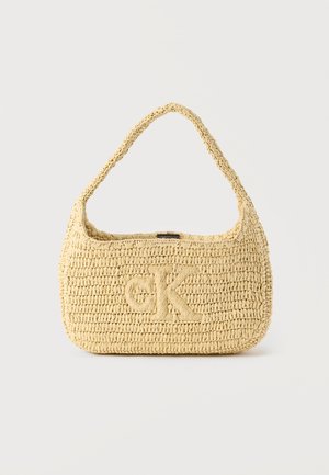 Vevd stråveske i beige med en buet form, enkelt skulderreim og preget "CK"-logo på forsiden. Teksturert, lett materiale.