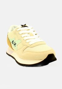 Sneaker beige con dettagli a forma di stella verde menta, lacci bianchi, materiali morbidi in tessuto e suede, suola nera e logo sulla linguetta.