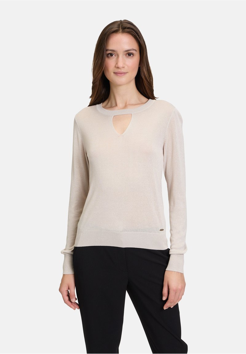 Pull en tricot beige clair avec un décolleté en forme de clé, des manches longues, des poignets côtelés et un ourlet ajusté. Agrémenté d'un petit logo.