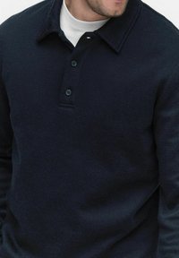 Marinblå texturerad tröja med krage, som har en treknapps knapplist, ribbat tyg och en subtil logo på kragen.