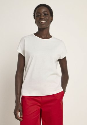 White short-sleeve t-shirt in soft fabric with a round neckline, paired with red high-waisted trousers, displayed on a plain background.