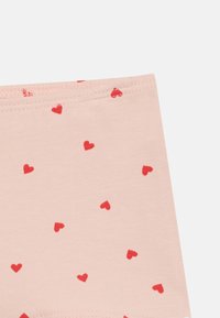 Υφάσμα σε ανοιχτό ροζ χρώμα με διάσπαρτο μοτίβο μικρών κόκκινων καρδιών και ραμμένο τελείωμα στην πάνω άκρη.