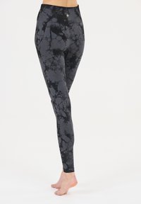 Leggings marbrés noir et gris en tissu extensible, avec une taille haute et un petit accent métallique à l'arrière.