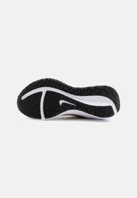 Černá gumová podrážka s texturovaným vzorem, bílá mezipodrážka a logo Nike swoosh. Navrženo pro trakci a stabilitu při sportovním využití.