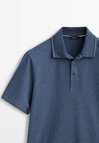 Polo shirt bleu foncé en tissu texturé, avec un col à couture contrastante, une patte de boutonnage à trois boutons et des manches courtes.