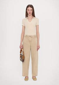 Beige ribbed short-sleeve top, high-waisted beige wide-leg pants, woven gold flats, and a brown patterned shoulder bag.