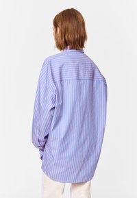 Blue and pink striped oversized shirt in cotton fabric. Features a classic collar, long sleeves, and button cuffs, with a back yoke detail.