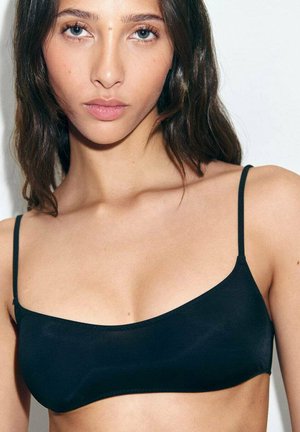 Zwarte bralette met dunne verstelbare bandjes, gladde textuur en een eenvoudig ontwerp. De stof lijkt elastisch, wat zorgt voor een aangesloten silhouet.