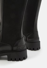 Botas de goma negra y textil con suela gruesa, acabado suave y un leve brillo. Diseñadas con un estilo duradero que se puede poner fácilmente.