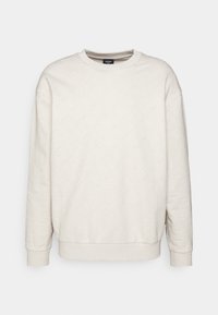 Lichtbeige sweatshirt met een gestructureerd patroon. Heeft een ronde hals, geribde manchetten en een relaxte pasvorm. Logo subtiel in het materiaal ingebracht.