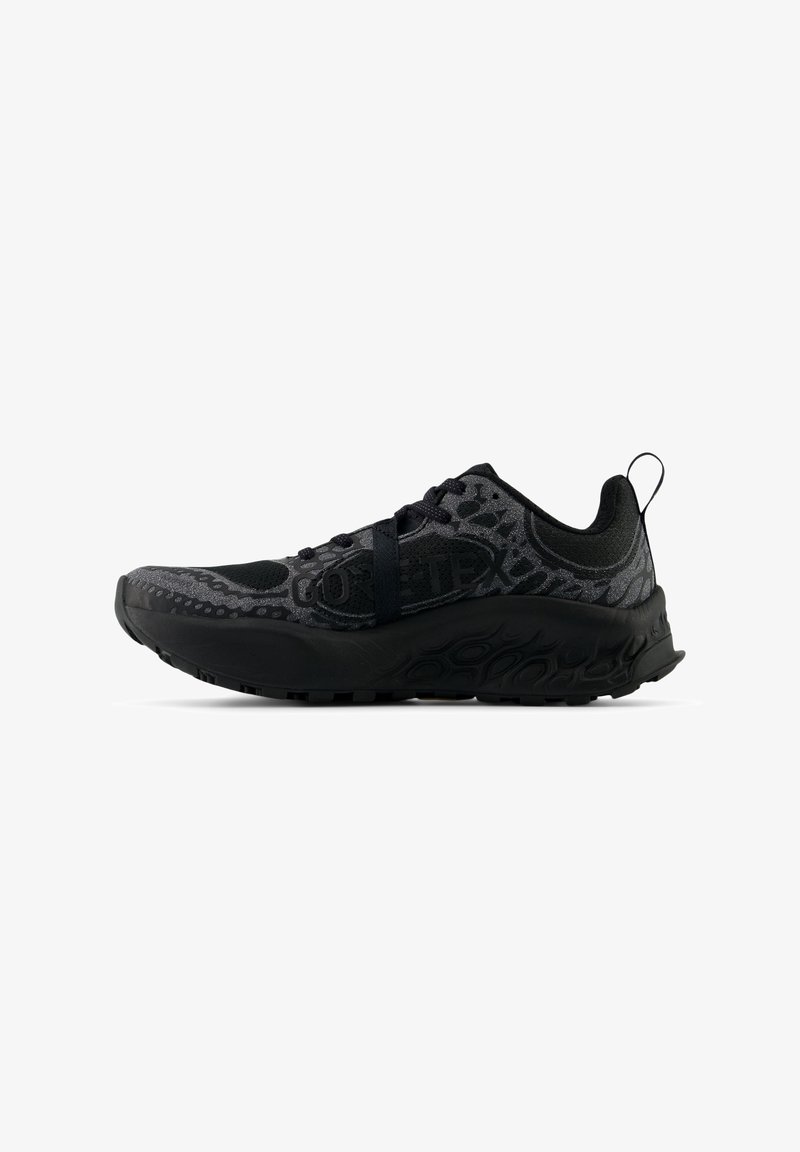 Chaussure de sport noire avec dessus texturé, semelle épaisse et rembourrée, languette au talon, et marquage Gore-Tex sur le côté.