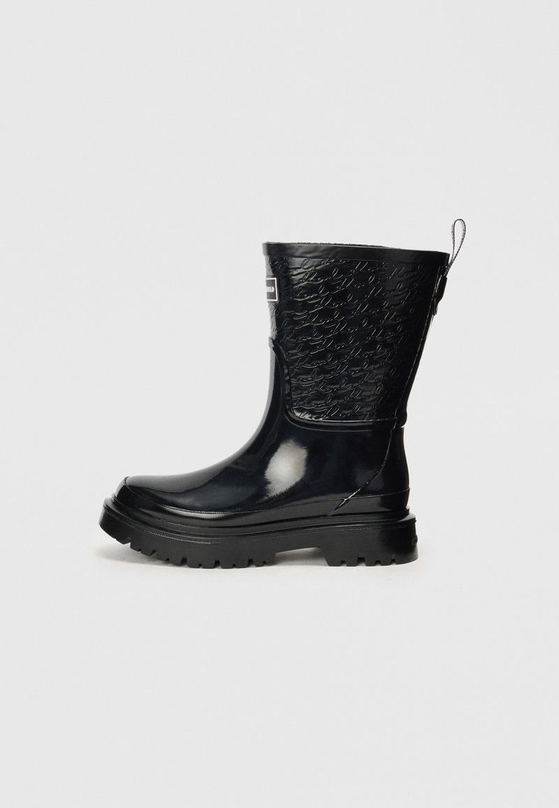 Bottes de cheville en caoutchouc noir avec une finition brillante, tige texturée présentant un motif en relief et une semelle robuste. Conçues avec une languette pour un enfilage facile.