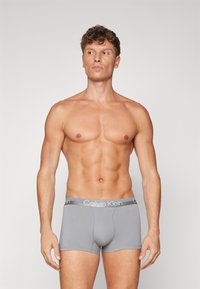 Pilkos boxer tipo kelnaitės su prigludusia forma, pagamintos iš medvilnės, turinčios lygią tekstūrą ir kontrastingą Calvin Klein logotipo juostą.