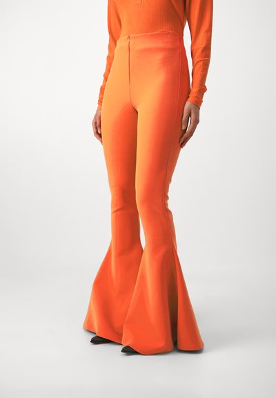 Flared orange pants made from a smooth, stretchy fabric with a high waist and a fitted shape, tapering to a wide flare at the hem.