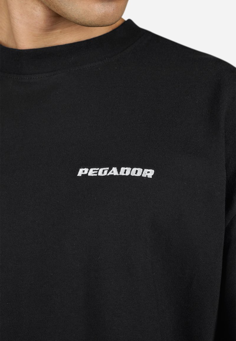 Czarna, długosleeve'owa koszula z miękkiej bawełny. Posiada białe logo "PEGADOR" na piersi oraz klasyczny krój z okrągłym dekoltem.
