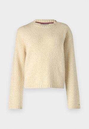 Pull-over beige en tricot à col rond avec de longues manches et des poignets et un ourlet côtelés, présenté sur un fond blanc uni.