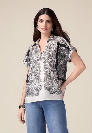 Korte mouw blouse van zijdeachtige stof met een zwart-wit paisley motief. Voorzien van een V-hals en een relaxed fit, geaccentueerd door zijzakken.