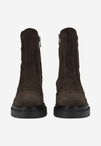 Bottes de cheville en daim marron avec une texture lisse, un bout rond, des zips latéraux et des semelles épaisses en caoutchouc noir. Design minimaliste avec des coutures verticales.