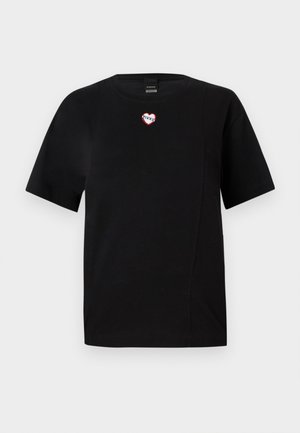 T-shirt noir à manches courtes en coton, présentant un patch en forme de cœur rouge et blanc avec "PINCO" sur la poitrine. Texture lisse, design minimaliste.