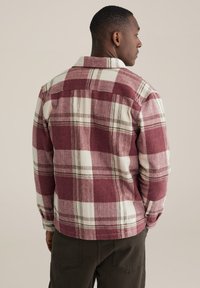 Rot-weiß kariertes Flanellhemd mit Kragen und Knopfverschluss, das eine weiche Textur und eine lockere Passform zeigt, von hinten betrachtet.