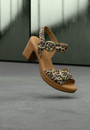 Open-toe sandalen met hoge hak en luipaardprint, met een kurkstijl zool en gouden hardware accenten op de riempjes. Gestrikt ontwerp met een blokhak.