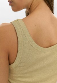 Golden knit tank top with ribbed texture, wide straps, and a scoop neckline, highlighting a soft, shimmering finish.