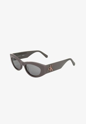 Occhiali da sole neri a forma di cat-eye con lenti scure e logo Calvin Klein "cK" rosa sulla asta.