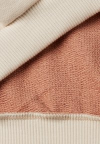 Cotton blend fabric showing a cream ribbed texture above a rosy pink terry cloth section with visible stitching on the edge.