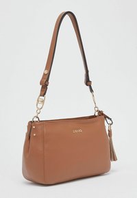 Sac à bandoulière en cuir marron avec un logo doré, des ferrures dorées, des accents noirs et un détail pompon. Comprend une seule sangle réglable.