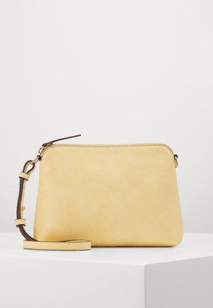 Petite pochette bracelet en cuir jaune clair avec fermeture éclair dorée et sangle réglable, présentée sur une surface blanche sur fond uni.