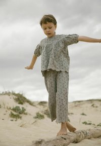 Completo in cotone grigio composto da una blusa con maniche a sbuffo e dettagli ricamati, abbinata a pantaloni coordinati. Il tessuto ha una consistenza delicata.