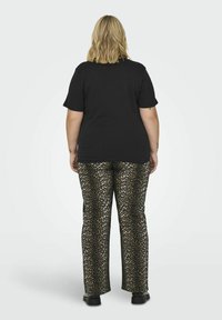 T-shirt preto de manga curta combinado com calças de padrão de leopardo com um padrão texturizado brilhante. Sapatos pretos sólidos completam o conjunto.