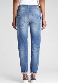 Hellblaue Denim-Jeans mit lockerem Schnitt, sichtbaren Nähten und einem umgeschlagenen Saum. Sie verfügen über zwei Gesäßtaschen und ein Markenetikett am Bund.