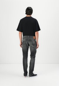 Tricou oversized negru asortat cu blugi skinny gri închis. Prezintă o petă din piele a mărcii și un design standard al buzunarului. Adidașii negri completează ținuta.