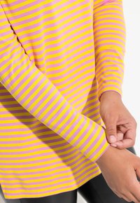 Maglietta a maniche lunghe a righe con colori alternati rosa e giallo, realizzata in tessuto morbido con maniche aderenti e scollatura rotonda.