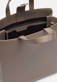 Taupe torba tote z wegańskiej skóry o gładkiej teksturze, z podwójnymi uchwytami, zamykaną kieszenią wewnętrzną oraz wytłoczonym logo marki w środku.