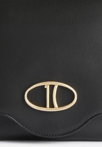Borsa a mano in pelle nera con un logo ovale dorato con "10" al centro. Texture liscia con dettaglio di cucitura a motivo ondulato.