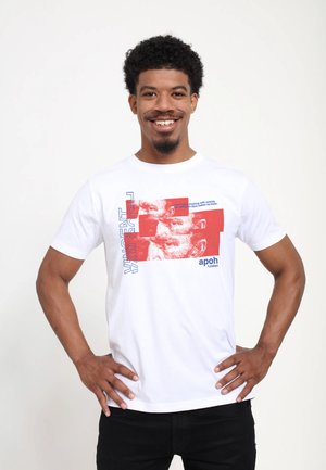 Hvid bomulds t-shirt med et rødt grafisk design, der indeholder textelementer og abstrakte ansigtstræk. Korte ærmer og rund halsudskæring.