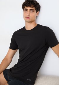 T-shirt noir à manches courtes en tissu doux, avec un col rond et un petit logo Diesel près de l'ourlet.