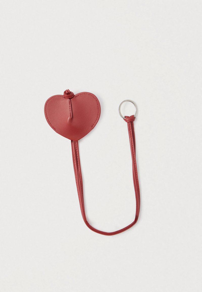 Portachiavi a forma di cuore in pelle rossa con finitura texturizzata, dotato di un cinturino abbinato e di un anello metallico per il fissaggio.