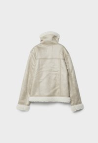 Béžová bunda z umělého beránku s měkkou texturou, vysokým límcem a bílým chlupatým lemováním na manžetách a spodním okraji. Obsahuje jemné šicí detaily.