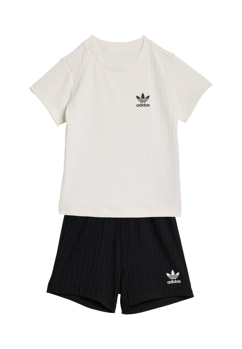 Conjunto de camiseta blanca de manga corta acanalada de Adidas con pantalones cortos negros acanalados de Adidas, que presentan los logotipos de trébol de Adidas en ambas prendas.