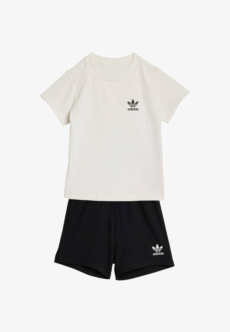 Conjunto de camiseta blanca de manga corta acanalada de Adidas con pantalones cortos negros acanalados de Adidas, que presentan los logotipos de trébol de Adidas en ambas prendas.
