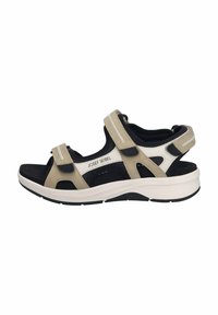 Beige ja must sandaal Velcro rihmadega, avatud varvastega disain, pehme sisetald ja paks valge ja must põhi. Brändi nimi on nähtav.