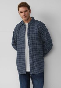 Marineblauwe geblokte overhemden met een spread collar, van katoen, met een borstzak, gedragen over een wit T-shirt, gecombineerd met blauwe jeans.