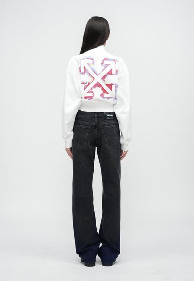 White sweatshirt with large red and blue graphic arrow design on back, paired with black wide-leg jeans. Soft fabric, relaxed fit.