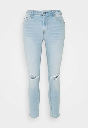 Jasnoniebieskie dżinsowe rurki z dwoma przetarciami na kolanach, pięcioma kieszeniami oraz standardowym pasem z zapinaniem na guziki z przodu.