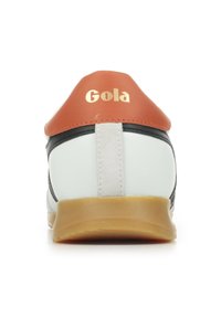 Sneaker bianco con accenti neri, tallone in pelle arancione e logo "Gola" dorato. Presenta una suola in gomma testurizzata e un materiale superiore liscio.